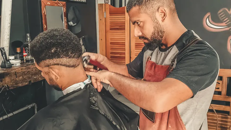 Een barbier knipt nauwkeurig het haar van een klant in een salon tijdens een opleiding uiterlijke verzorging.