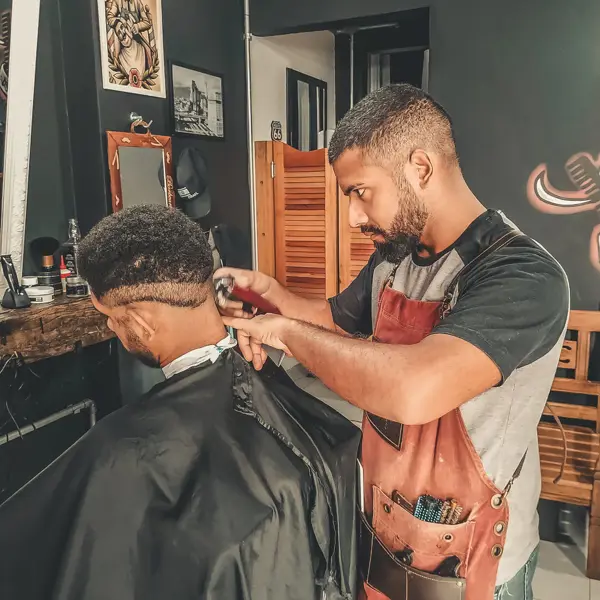 Een barbier knipt nauwkeurig het haar van een klant in een salon tijdens een opleiding uiterlijke verzorging.