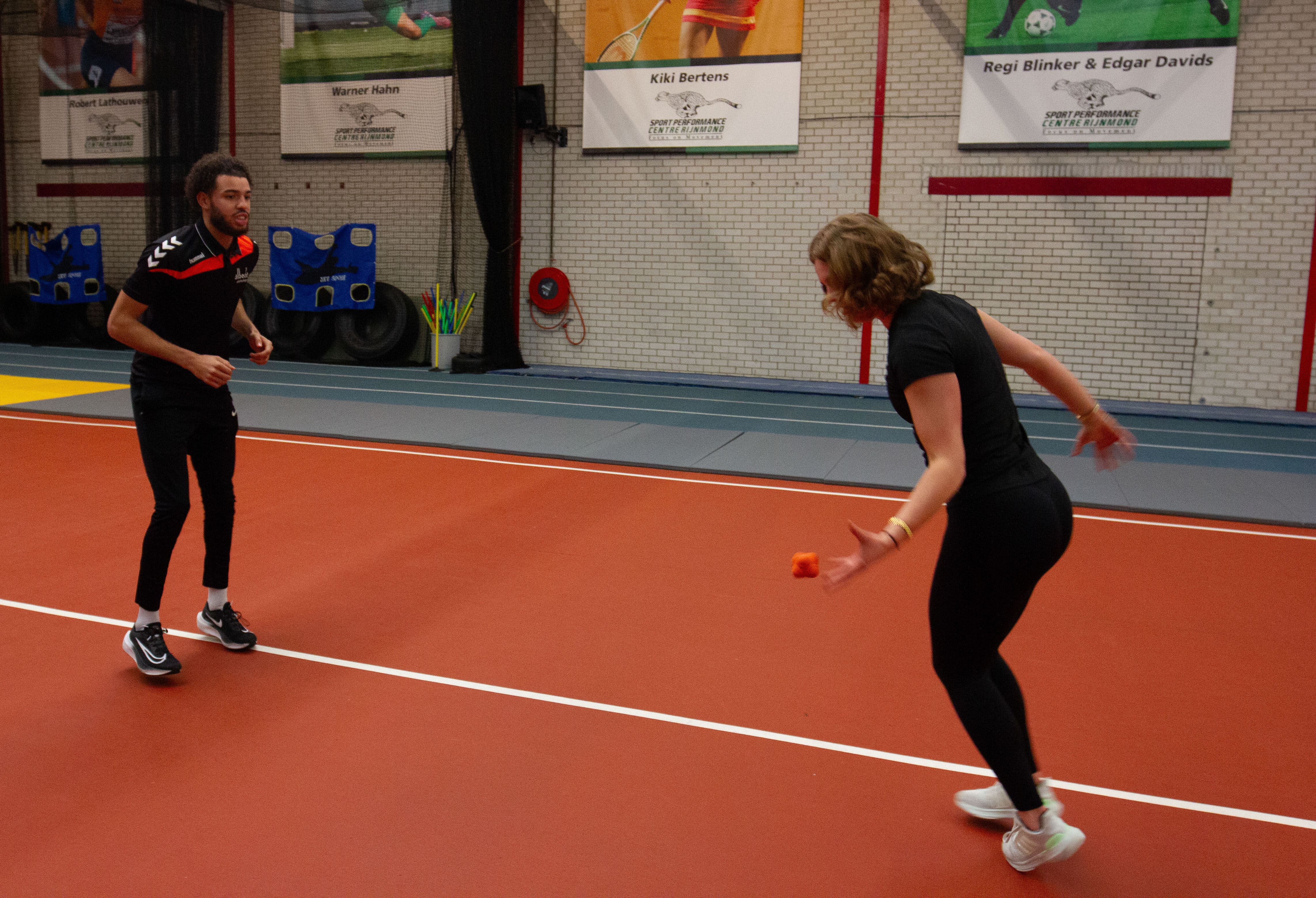Twee sportbegeleiders oefenen coördinatie en beweging op een indoor sportvloer