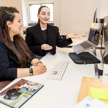 Twee studenten bespreken informatie op een laptop tijdens een les in de welzijnssector.