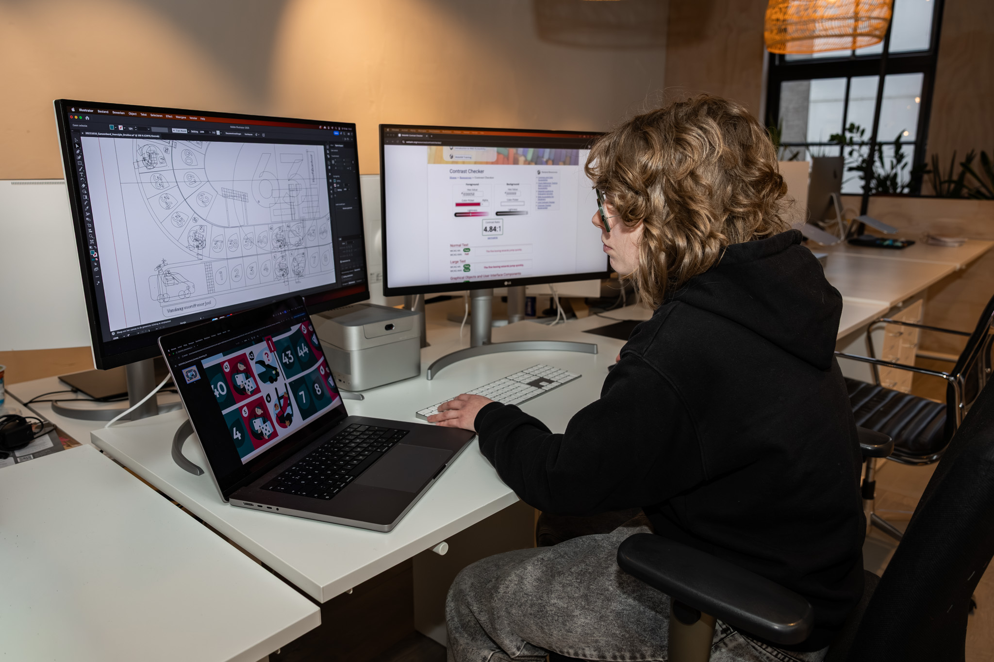 Student werkt zelfstandig met grafische software op meerdere schermen aan mediaproducten