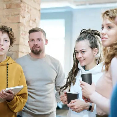 Groep studenten bespreekt marketing- en communicatieprojecten tijdens een informele bijeenkomst.
