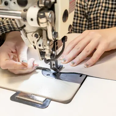 Leerling voert nauwkeurig werk uit met een naaimachine, gericht op ambachtelijk vakmanschap.