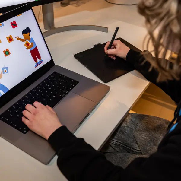 Student werkt met tekentablet aan digitale illustraties voor mediaproducten in communicatie en design