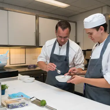 Studenten in professionele keuken bereiden samen een gerecht tijdens een mbo-opleiding leidinggevende keuken