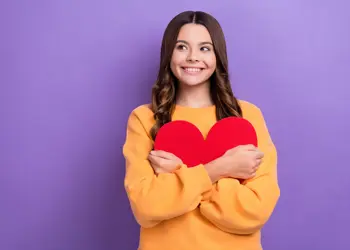 Jonge studiekiezer houdt hartvormig voorwerp vast en kijkt enthousiast ter inspiratie
