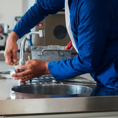 Keukenmonteur sluit waterleiding aan bij de spoelbak tijdens het installeren van een keukenruimte