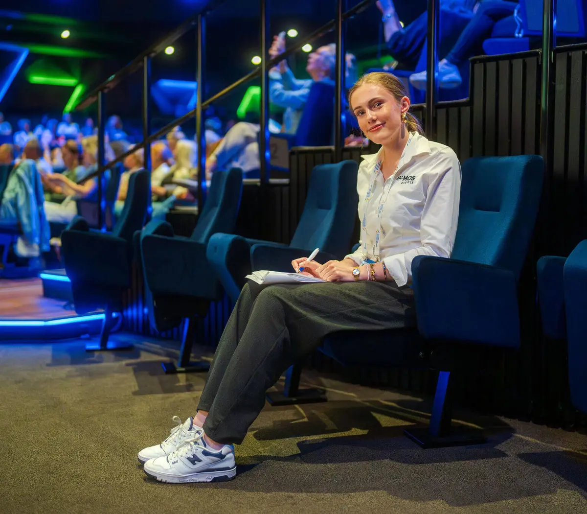 Medewerker evenementenorganisatie houdt notities bij tijdens een evenement in een auditorium.