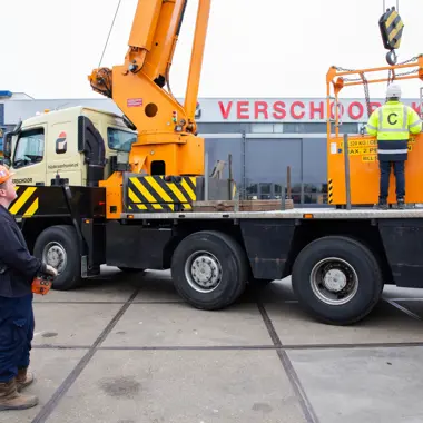 Twee medewerkers bedienen een hijskraan voor werkzaamheden in de infrastructuursector.
