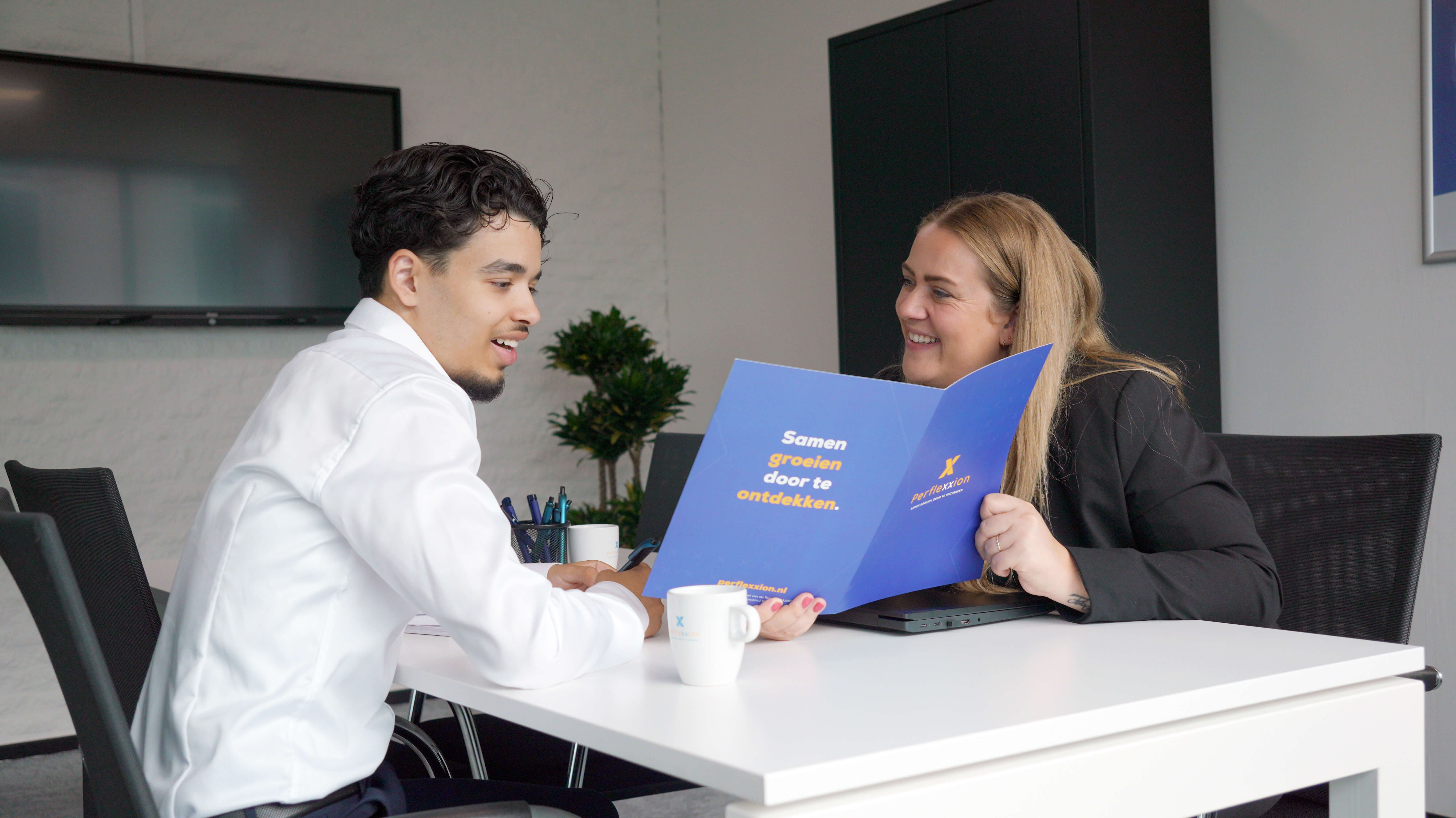 Consulent commerciële arbeidsbemiddeling bespreekt met student kansen en contracten in een kantooromgeving