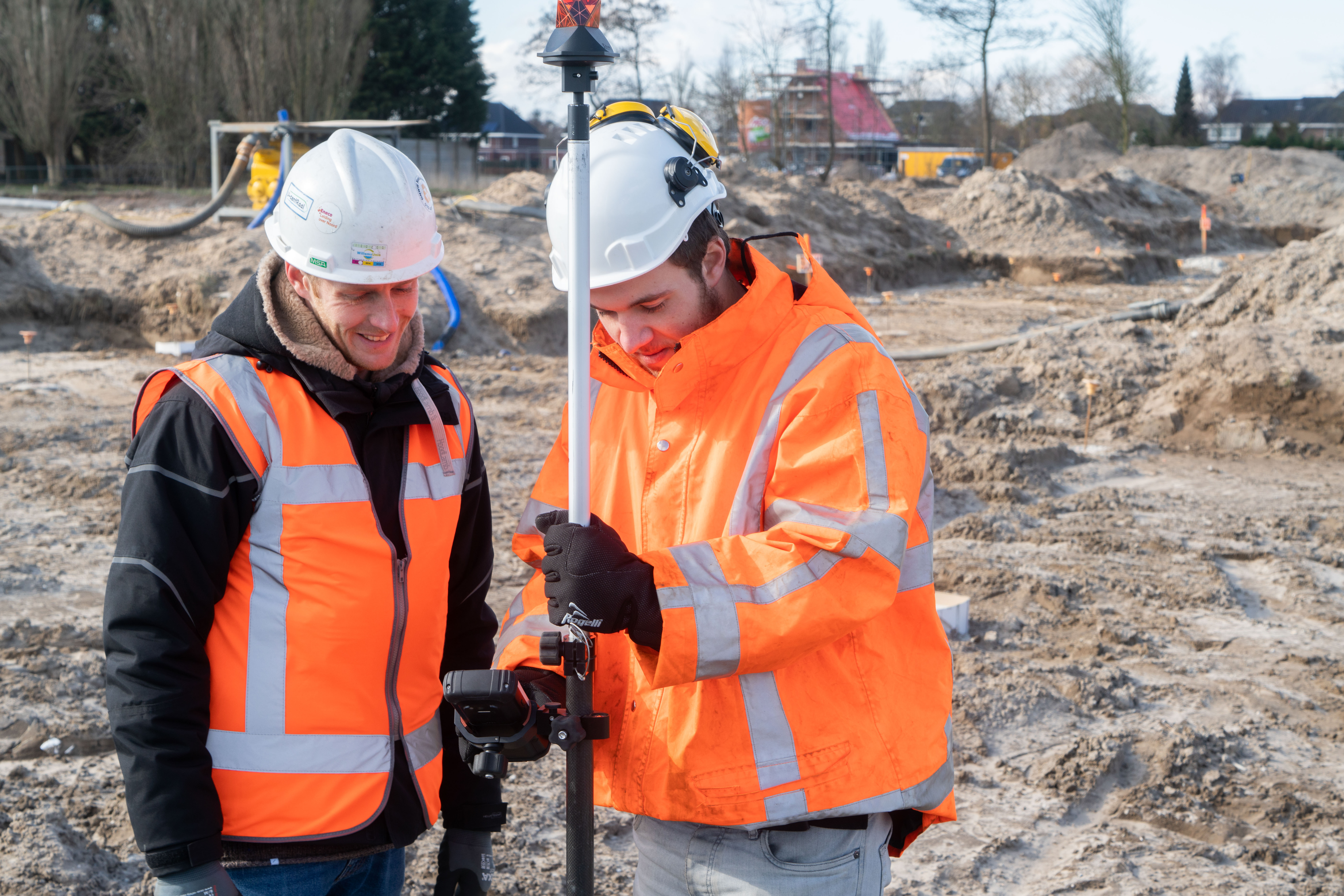 Middenkaderfunctionarissen landmeetkunde werken met meetapparatuur op een bouwlocatie voor wegen- en vastgoedprojecten