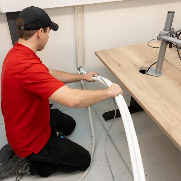 Monteur bereidt technische installatie voor door buizen en kabels te plaatsen in een werkruimte