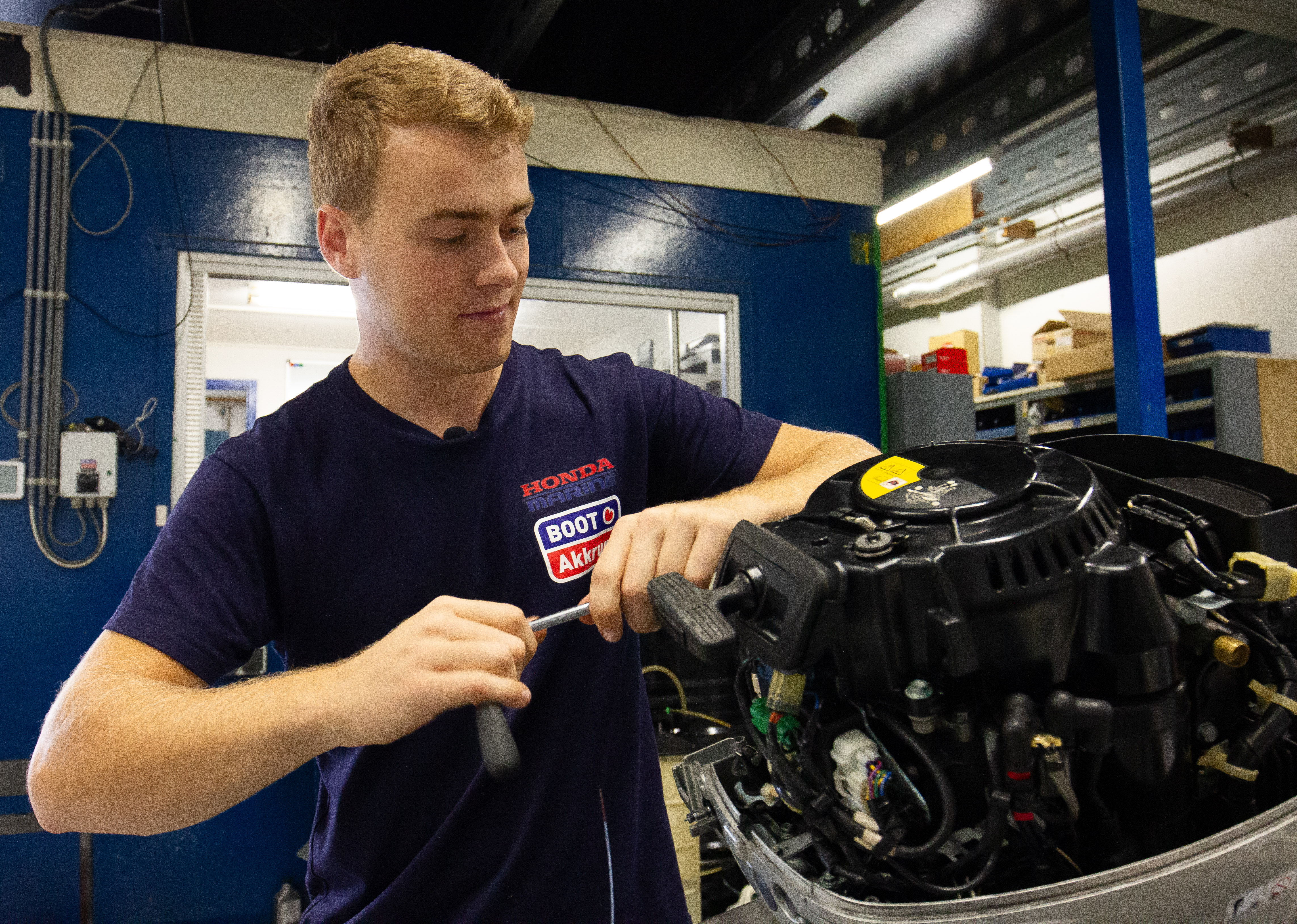Student werkt aan het onderhoud van een buitenboordmotor in een technische werkplaats voor maritieme techniek