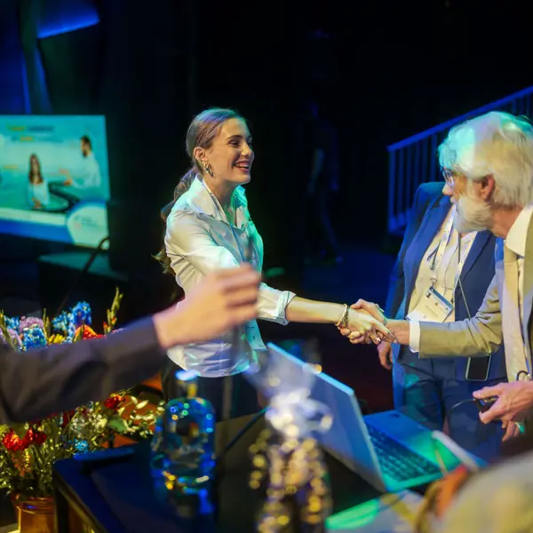 Een organisator verwelkomt een bezoeker tijdens een evenement gericht op marketing en communicatie.