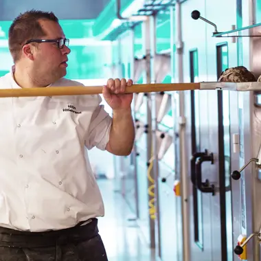 Bakker plaatst versgebakken broden in de oven tijdens het bereiden van ambachtelijk gebak.