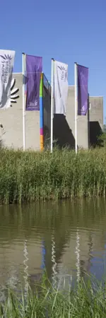 ROC Midden Nederland gebouw aan Harmonielaan 2 met vlaggen en waterpartij op de voorgrond