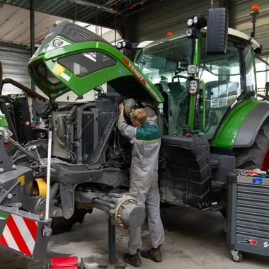 Monteur voert onderhoud uit aan tractor in werkplaats gericht op mobiliteit en techniek