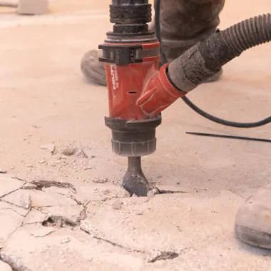 Vakman gebruikt boorhamer om beton te breken in een bouwproject