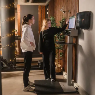 Begeleider legt sporter uit hoe fitnessapparaat te gebruiken voor training en beweging