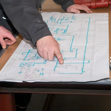 Technicus industriële koude- en klimaatsystemen wijst onderdelen aan op technische tekening voor installatie of onderhoud.