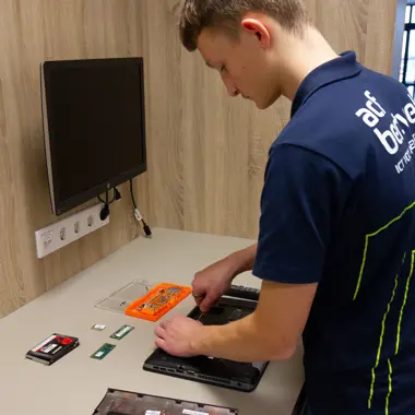 Een leerling demonstreert het repareren van een laptop als onderdeel van een ICT-opleiding.