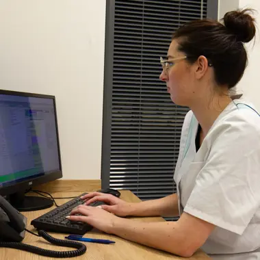 Medewerker in de zorg werkt geconcentreerd met computer en geeft professioneel advies over uiterlijke verzorging