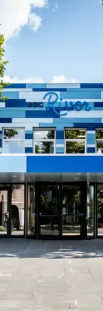 Entree van het ROC Rivor gebouw aan de Bachstraat met ingang en boven de naam van de school.