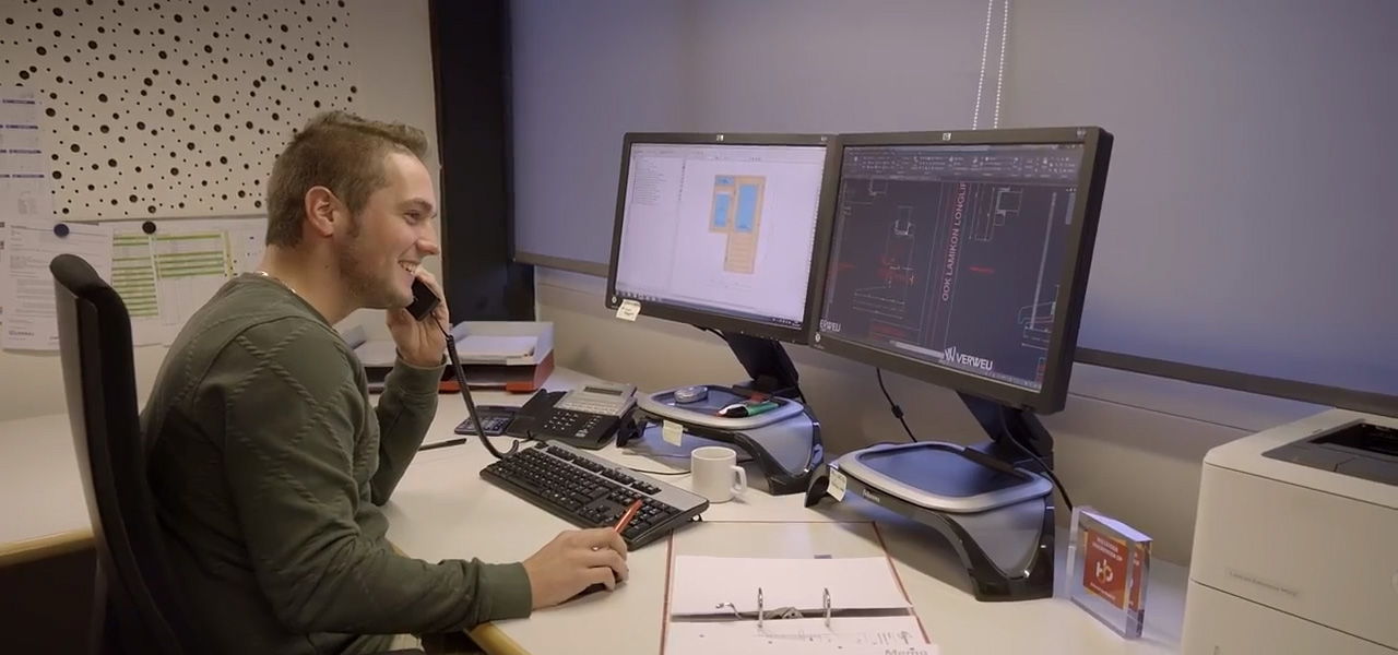Werkvoorbereider houttechniek bespreekt via telefoon en controleert technische tekeningen op computerschermen
