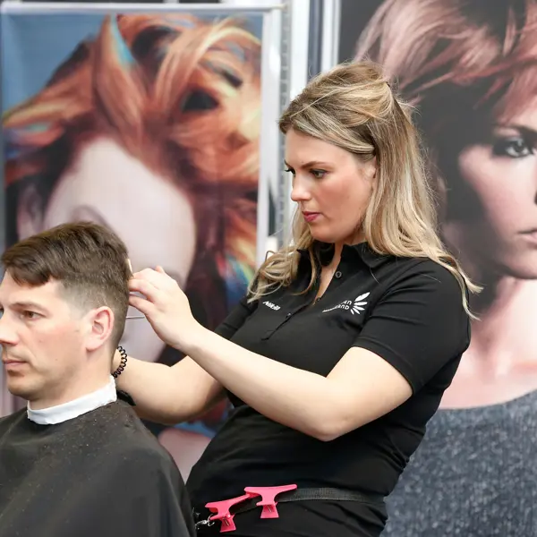 Barbier die haar knipt en stijlt in een salon, gespecialiseerd in verzorging van herenkapsels.