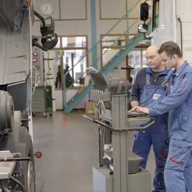 Technische studenten controleren en diagnosticeren een vrachtauto in een werkplaats voor mobiliteit en transport.