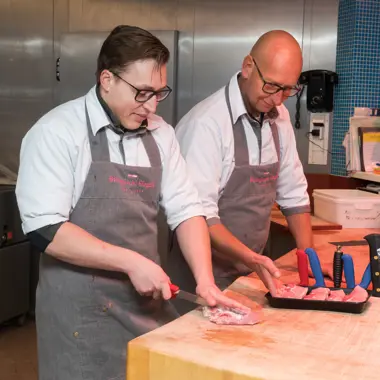 Twee vakbekwame medewerkers bereiden vers vlees in een professionele winkelomgeving
