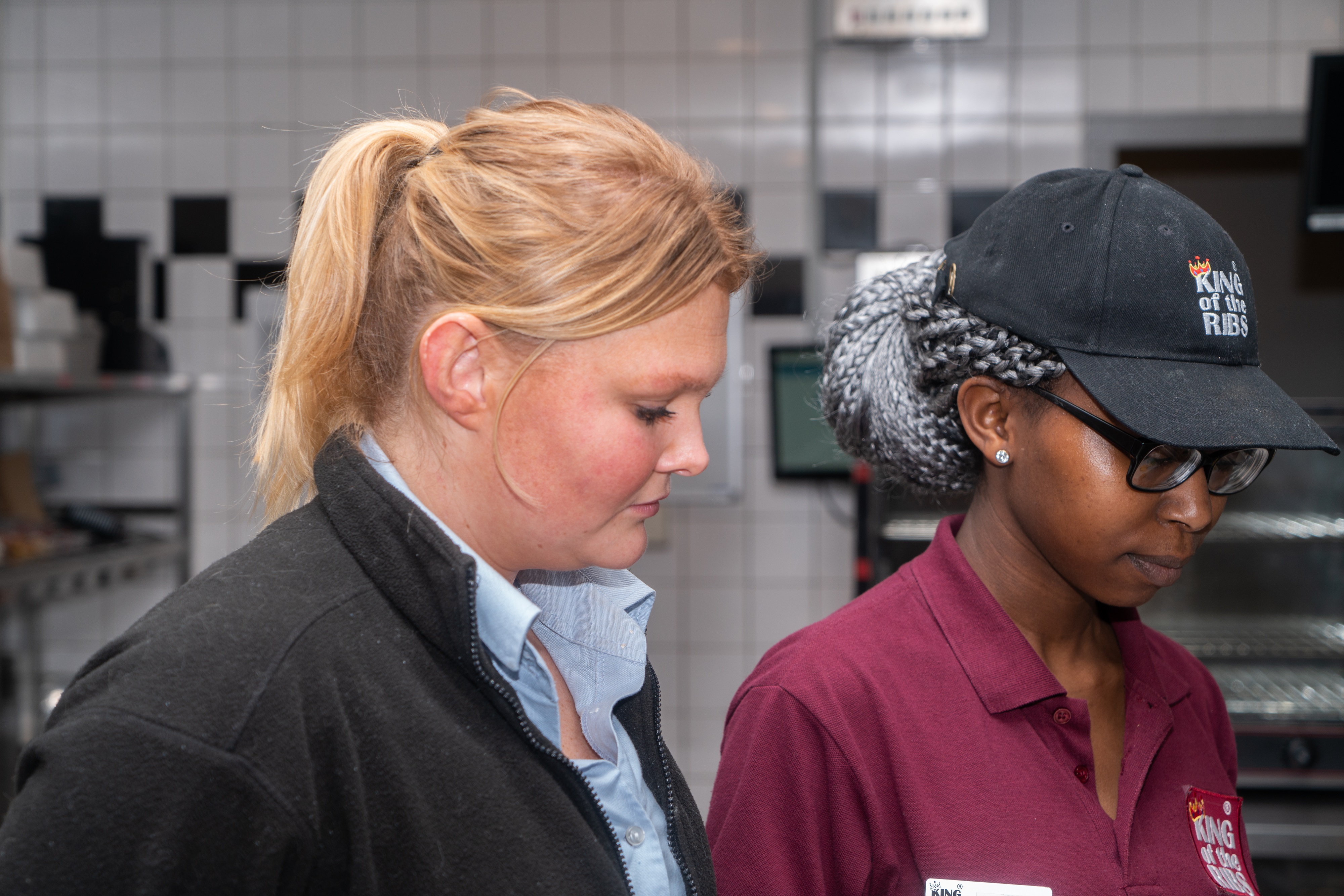 Twee medewerkers in een professionele keuken bespreken werkzaamheden tijdens de fastservice opleiding.