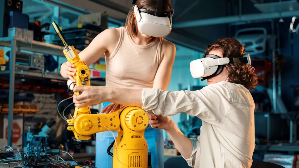 Twee studenten werken samen met een robotarm in een technische leeromgeving met VR-brillen.