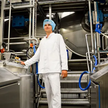 Medewerker in productieruimte van voedingsbedrijf controleert apparatuur voor gezonde maaltijdproductie.