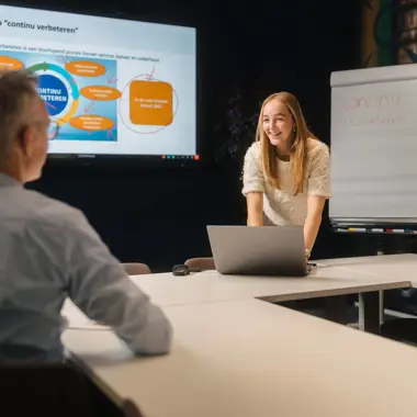 Marketingcommunicatiespecialist bespreekt strategie voor continu verbeteren tijdens overleg.