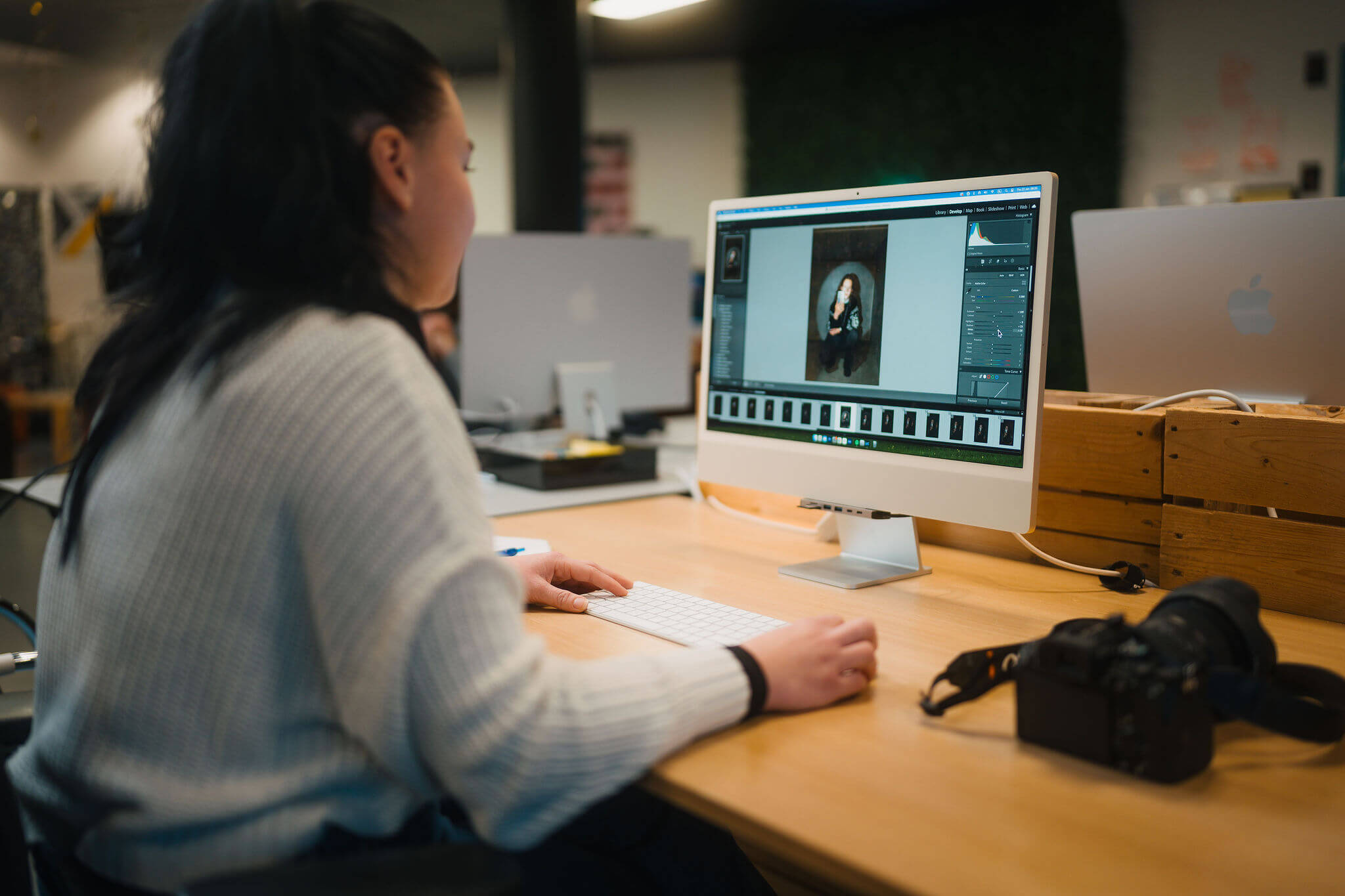 Een student bewerkt digitale fotografie op een computer in een creatief werkruimte.