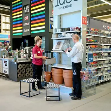 Medewerker helpt klant met producten in winkel, gericht op verkoop en klantcontact binnen retailomgeving