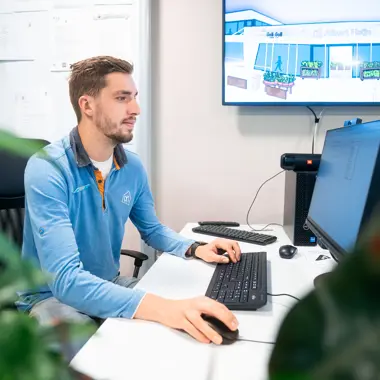 Een medewerker analyseert winkelpresentatie op computerscherm in een kantooromgeving gericht op retail.