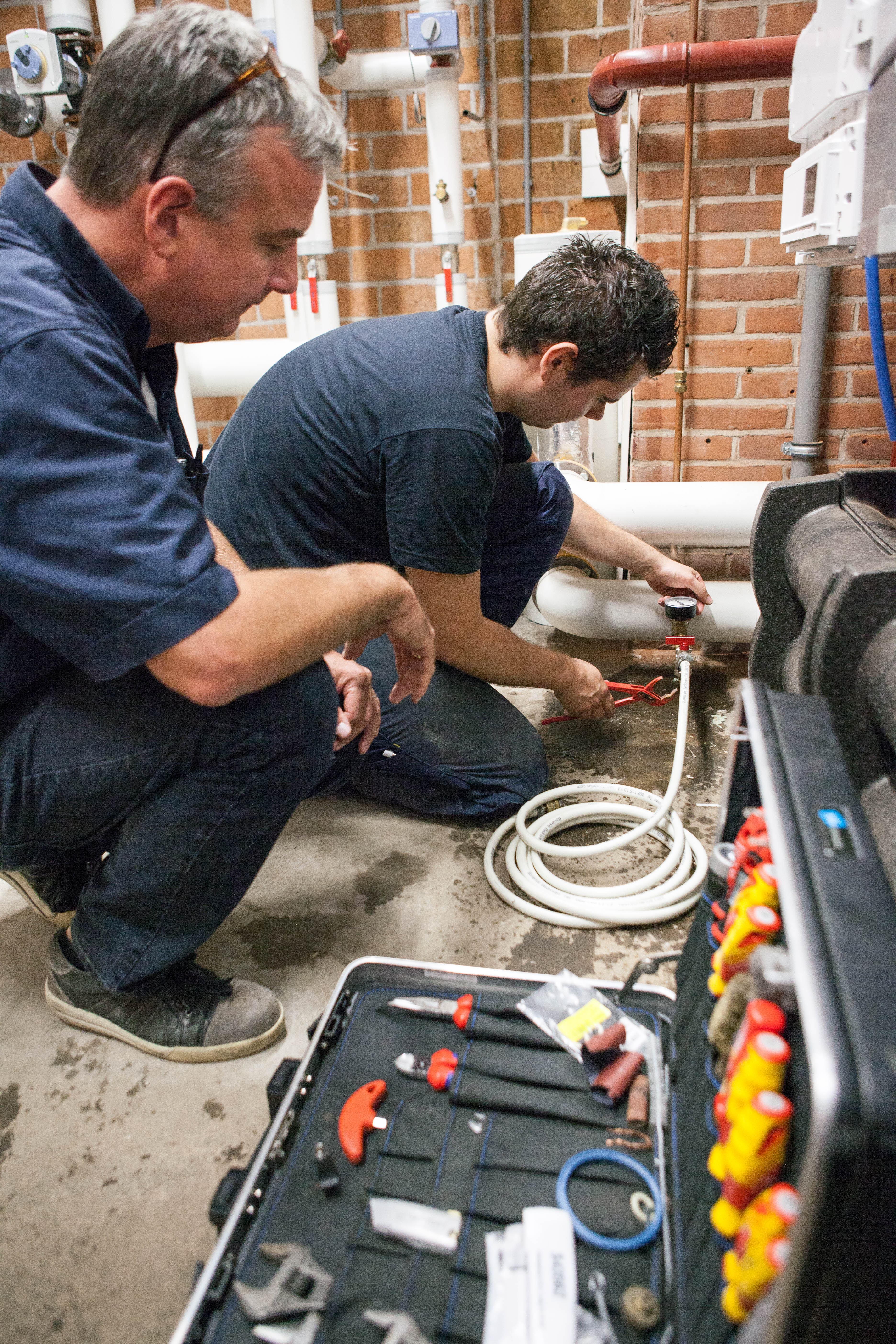 Twee monteurs voeren onderhoud uit aan leidingen en regelventielen in een techniekruimte