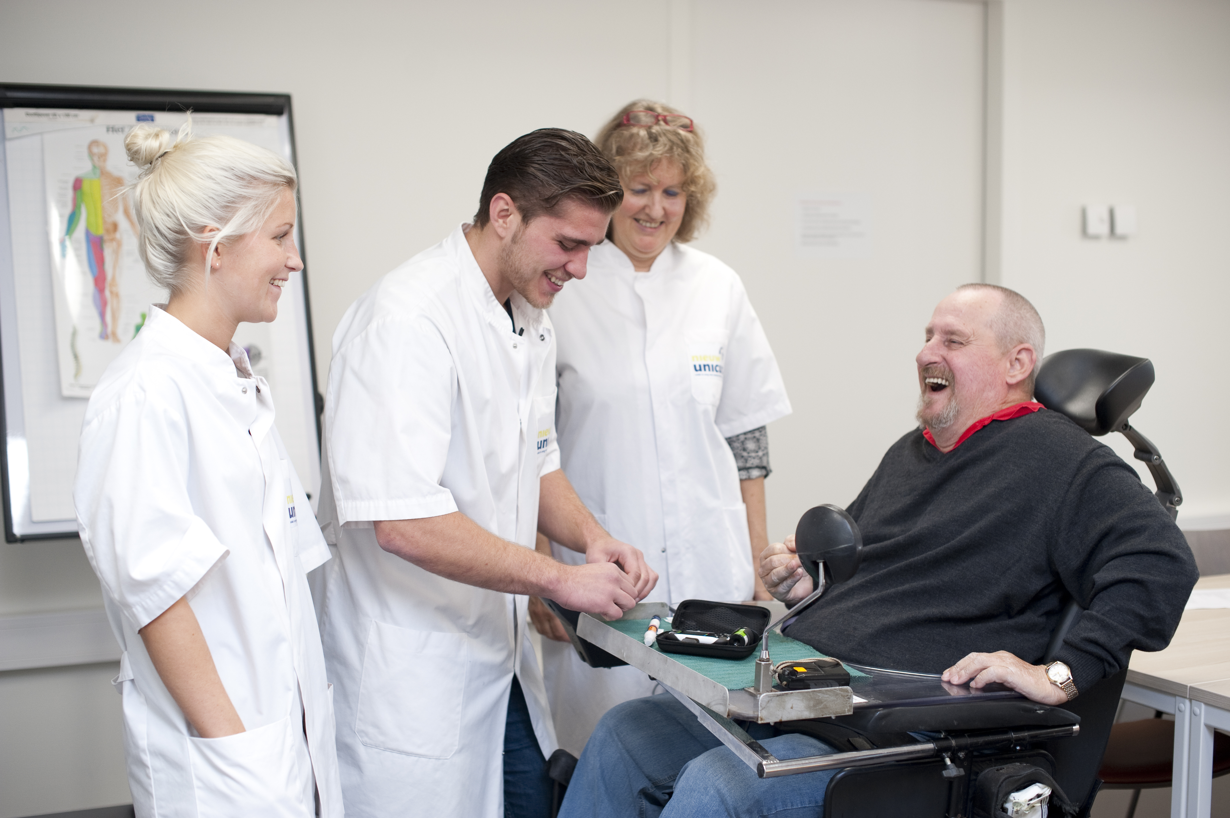 Verpleegkundestudenten voeren een handeling uit bij een patiënt in rolstoel in zorgomgeving