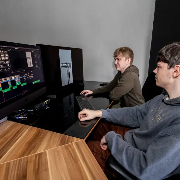 Twee studerende aan een professioneel editstation met videobewerkingssoftware in een mediastudio