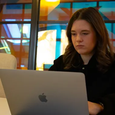 Student werkt geconcentreerd aan communicatieproject op laptop in een creatieve leeromgeving