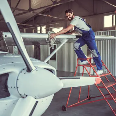 Medewerker reinigt zorgvuldig het oppervlak van een vliegtuig in een hangar, gericht op onderhoud en schoonmaak