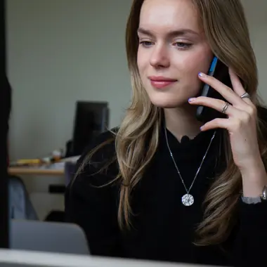 Student marketingcommunicatie voert telefonisch overleg terwijl ze achter een laptop werkt