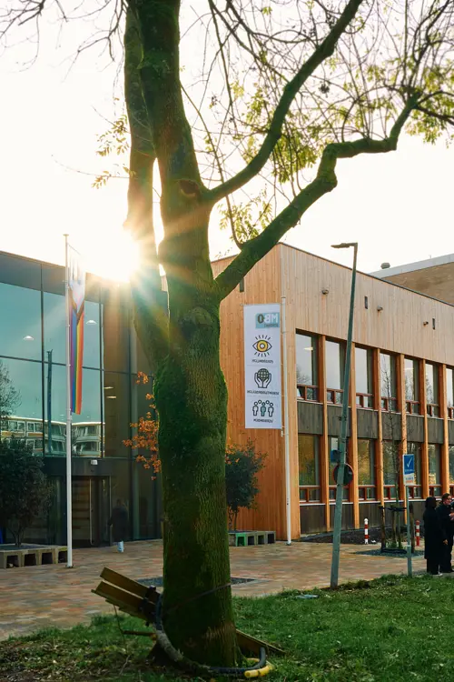 Gebouw van mbo Utrecht aan Australielaan 25 met groep studenten buiten op het grasveld