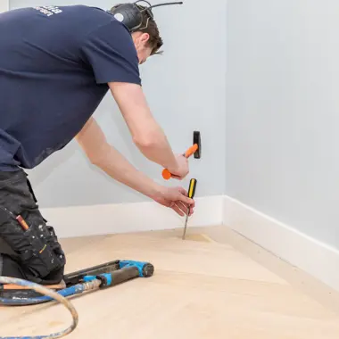 Vakspecialist plaatst vloerafwerking met precisie in een moderne woonruimte.