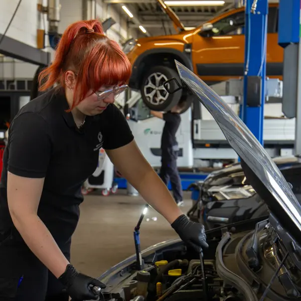 Technisch specialist onderzoekt motorruimte van personenauto in een werkplaats voor mobiliteit en techniek.