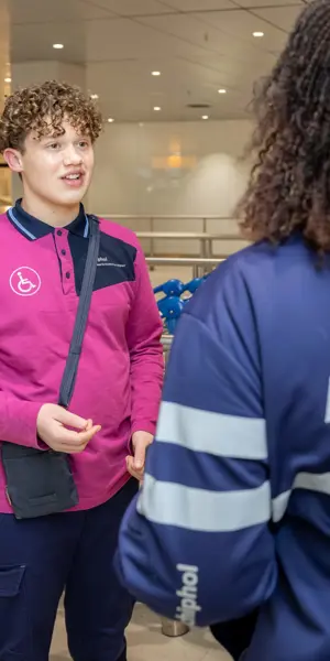 Een luchtvaartdienstverlener in gesprek met een collega die ondersteuning biedt aan passagiers met speciale behoeften.