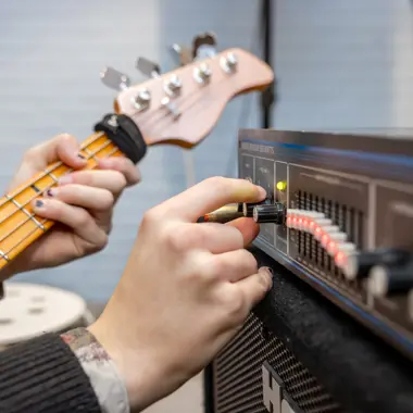 Een muzikant stemt een elektrische basgitaar met behulp van een versterker voor een live optreden.