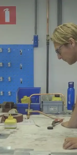 Twee monteurs werken samen aan metalen dak- en gevelonderdelen in een praktijkruimte.